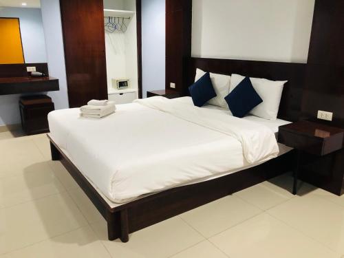 a bedroom with a bed with white sheets and blue pillows at Royal Star Suites pattaya in Pattaya South