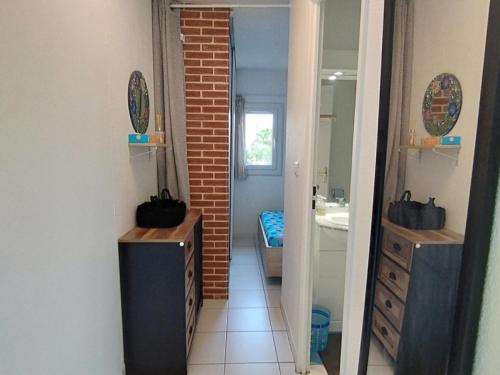 La salle de bains est pourvue d'un miroir et d'un mur en briques. dans l'établissement T2 Saint-Pierre-La-Mer - Parking - 3/4 pers - FR-1-795-63, à Fleury