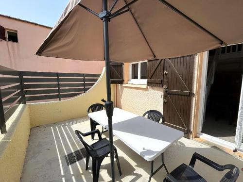 - une table et des chaises sous un parasol sur la terrasse dans l'établissement Maison proche plage avec terrasse et parking - FR-1-837-8, à Argelès-sur-Mer