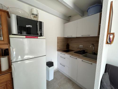 La cuisine est équipée d'un réfrigérateur blanc et d'un four micro-ondes. dans l'établissement Maison proche plage avec terrasse et parking - FR-1-837-8, à Argelès-sur-Mer