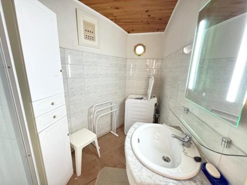 une salle de bain blanche avec un lavabo et une chaise dans l'établissement Maison de charme au cœur du Moulleau, 4 couchages - FR-1-474-279, à Arcachon