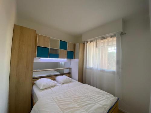 une petite chambre avec un lit blanc et une fenêtre dans l'établissement T2 à 200m de la plage avec terrasse et parking - FR-1-413-258, à Capbreton