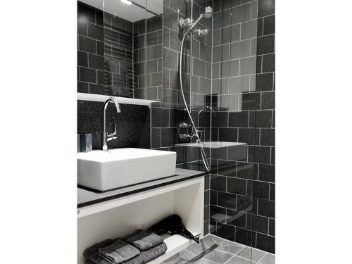 ein schwarz-weißes Badezimmer mit Waschbecken und Dusche in der Unterkunft Lüttjer Kaiser Comfortable holiday residence in Norderney