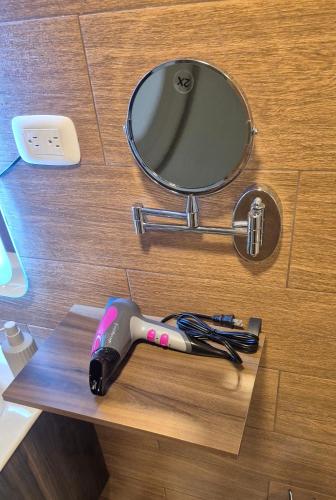 a hair dryer on a wooden counter with a mirror at A good rest upon arrival or departure from your trip just 7 minutes from El Salvador's airport in Las Flores