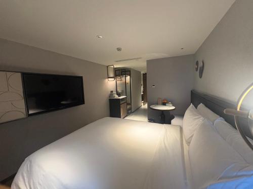 a bedroom with a white bed and a flat screen tv at Atour X Hotel West Nanjing Road in Shanghai