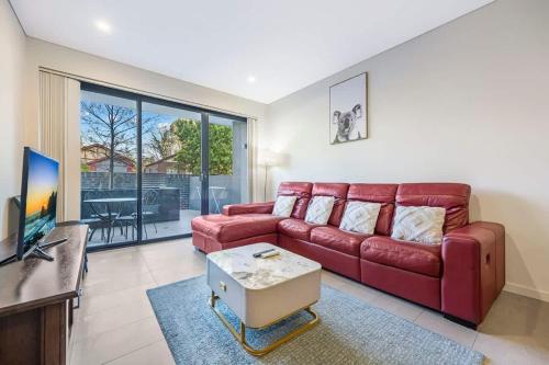 a living room with a red couch and a tv at Comfy 3 bed near DFO Sydney Olympic Park in Sydney