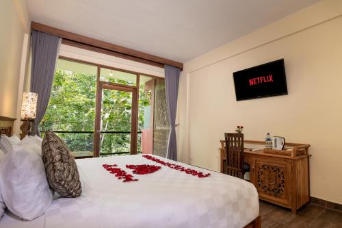 a bedroom with a bed with red roses on it at Umah Temuku Ubud in Ubud
