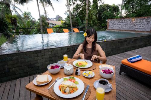 a woman sitting at a table with a plate of food at Umah Temuku Ubud in Ubud