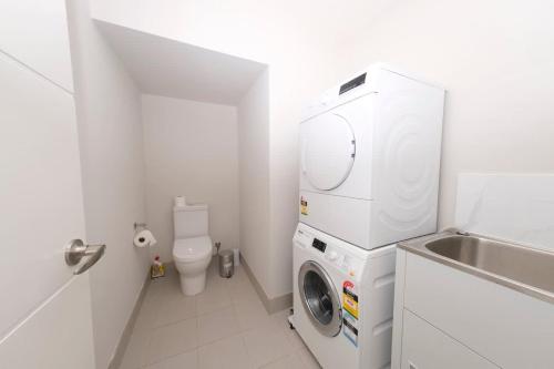 a bathroom with a washing machine and a toilet at Modern 4 Bedroom House in Box Hill in Riverstone