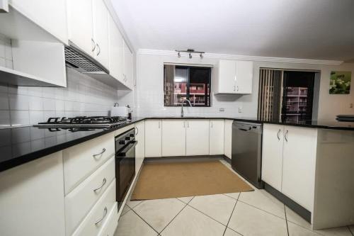 a white kitchen with white cabinets and a sink at Two Level 3 Bedroom Penthouse in Sydney Liverpool in Liverpool