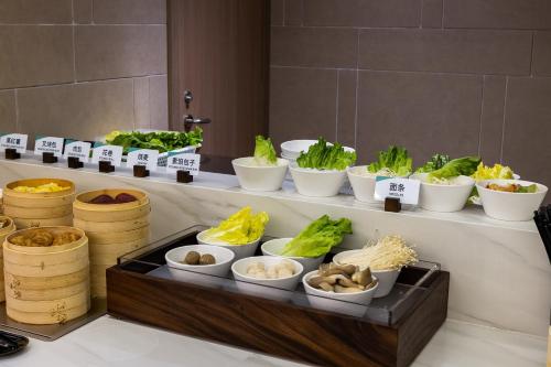 a buffet with bowls of food on a counter at Atour Hotel Shenzhen Futian CBD Gangxia North Metro Station in Shenzhen