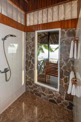 a bathroom with a shower and a window with a bench at Nunukan Island Resort in Maratua Atoll