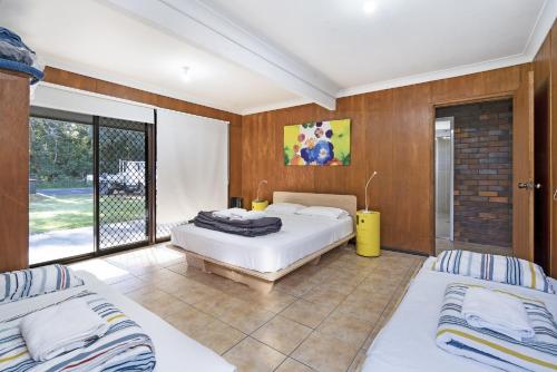 a bedroom with two beds and a balcony at Ammaboolah at Hat Head - 36 Hutcheson Street in Hat Head