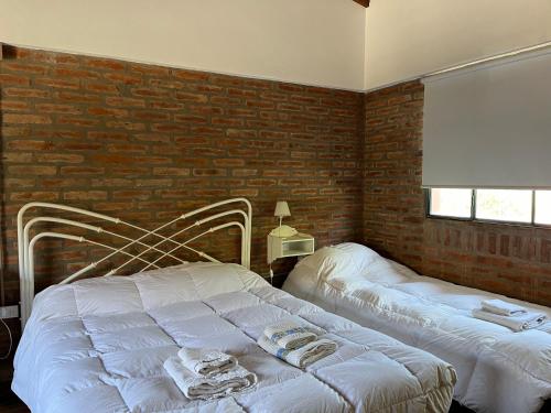 una camera da letto con due letti e un muro di mattoni di La Floridita a Puerto Pirámides