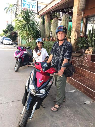 an older man is standing next to a motorcycle at TR Guesthouse in Sukhothai