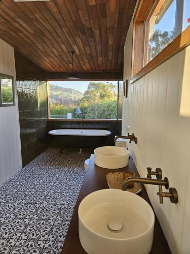 a bathroom with two sinks and a bath tub at Homeo Alpine Cottage in Omeo