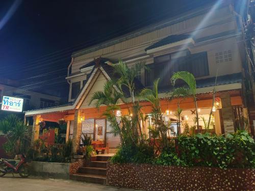 a building with plants in front of it at night at TR Guesthouse in Sukhothai