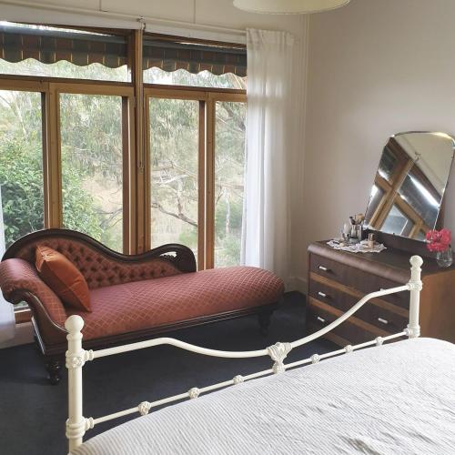 a bedroom with a bed and a mirror and a dresser at Homeo Alpine Cottage in Omeo