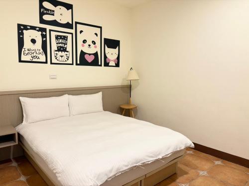 a bedroom with a white bed with pictures on the wall at Mulin B&B in Hengchun