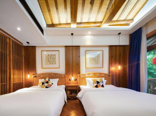 two beds in a room with wood paneling at Zhangjiajie Ldyllic Pondside Timber Lodge in Zhangjiajie