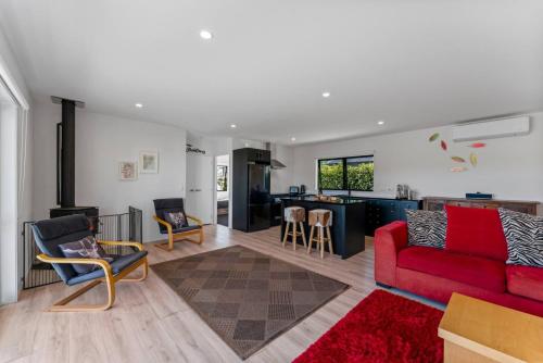 a living room with a red couch and a kitchen at Dragonflys Rest in Kinloch
