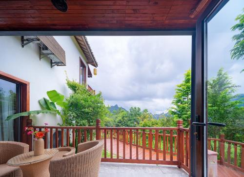 a balcony with chairs and a view of the mountains at Zhangjiajie Ldyllic Pondside Timber Lodge in Zhangjiajie