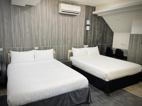 two beds in a hotel room with white sheets at Shigang Homestay市港行旅 in Jinhu