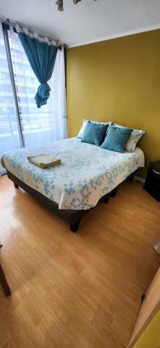a bedroom with a bed with blue pillows and a window at Apartamento Metro Santa Lucia, Santiago Centro in Santiago