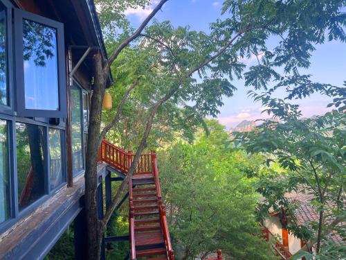 a ladder leading up to a house with a tree at Zhangjiajie Ldyllic Pondside Timber Lodge in Zhangjiajie