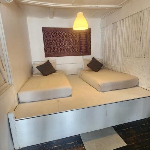 two beds in a small room with a light fixture at Coral Reef Holidays in Tioman Island