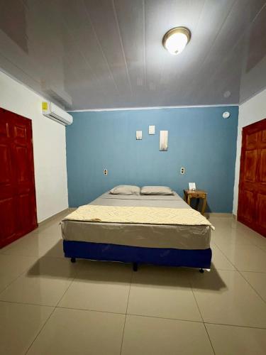 a bedroom with a bed in a blue wall at Hostal Sunset Town in Ahuachapán