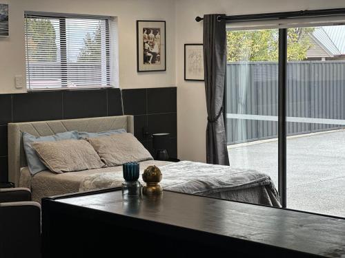 a bedroom with a bed and a large window at Easy Peasy Open-plan Studio in Hanmer Springs
