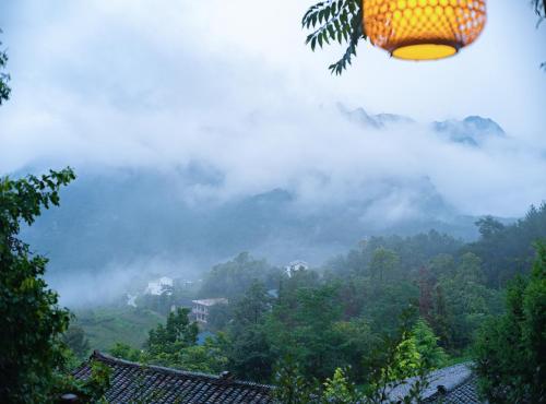 a room with a view of a mountain with clouds at Zhangjiajie Ldyllic Pondside Timber Lodge in Zhangjiajie