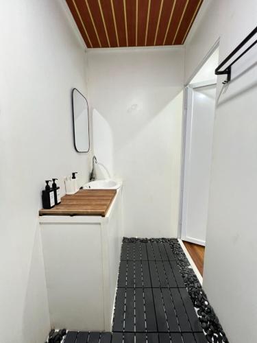 a bathroom with a sink and a black tile floor at Nira Meraki Aruna in Bedoyo