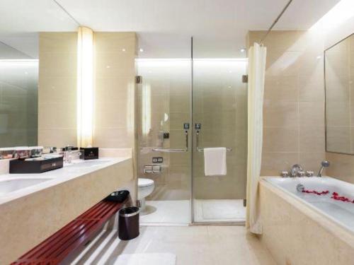 a bathroom with a shower and a tub and a sink at Wuhan Soluxe Hotel in Wuhan