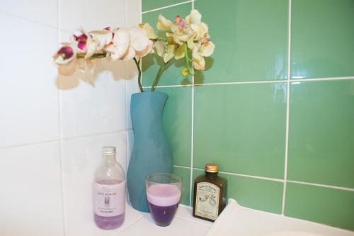 un vase bleu avec des fleurs et une boisson sur un comptoir dans l'établissement Oxford St Apartment with Gym Spa Pool, à Sydney