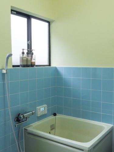 a bath tub in a bathroom with blue tiles at 一棟貸切の宿 えんの家 in Tsushima