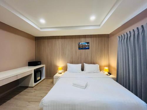 a bedroom with a large white bed and a tv at USABAI Riverside Boutique Hotel in Chanthaburi