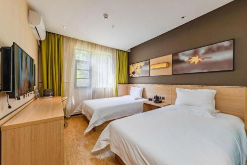 a hotel room with two beds and a flat screen tv at IU Hotel Kunming Jinma Bijifang Joy City in Kunming