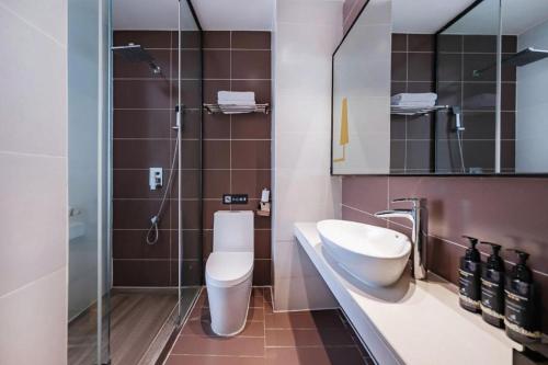 a bathroom with a toilet and a sink and a shower at IU Hotel Kunming Jinma Bijifang Joy City in Kunming
