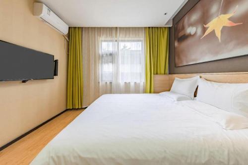 a bedroom with a large white bed and a flat screen tv at IU Hotel Kunming Jinma Bijifang Joy City in Kunming