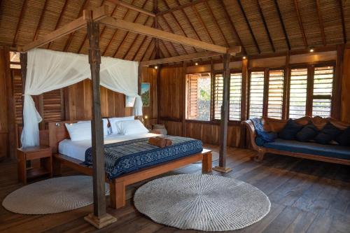 a bedroom with a canopy bed and a couch at Rote Beach House in Nembrala