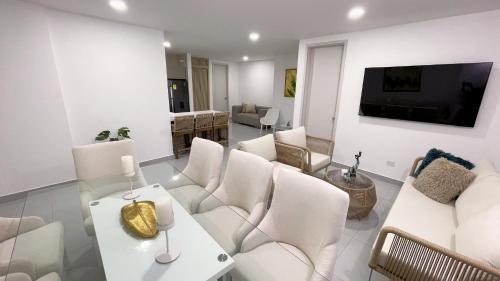 a living room with white furniture and a tv at Azure apartahotel in Santa Marta