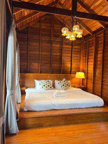 a bedroom with a bed in a room with wooden walls at Bann Rai I Na in Phrae
