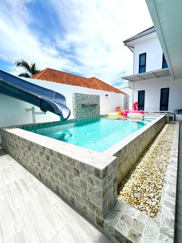 a swimming pool with a slide in a house at The White House Pool Villa Pattaya in Jomtien Beach