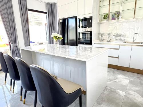a kitchen with a white counter and blue chairs at The White House Pool Villa Pattaya in Jomtien Beach