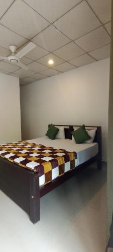a bedroom with a bed with a checkered blanket at New Summer Set Inn in Dambulla