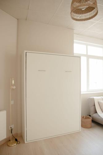 - un grand écran blanc dans le salon avec un canapé dans l'établissement Studio meublé Le Refuge doré avec Netflix, à Homécourt