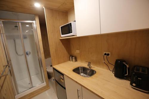 a small kitchen with a sink and a microwave at Self-contained Tiny Sleepout in Hamner in Hanmer Springs
