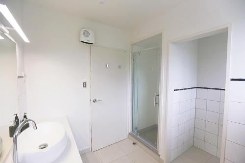 a white bathroom with a shower and a sink at Stunning Mountain Views in Renovated Hamner Home in Hanmer Springs
